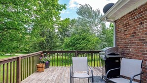 A wooden deck with a barbecue grill, two chairs, and a glass table. - Charming 3-bedroom house in peaceful Saint Francis, on the Bourbon Trail (Saint Francis)