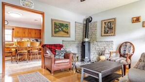 A living room with a fireplace, wooden furniture, and a kitchen in the background. - Charming 3-bedroom house in peaceful Saint Francis, on the Bourbon Trail (Saint Francis)