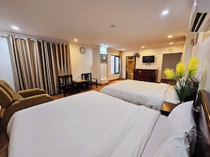 Een hotelkamer met twee bedden, een bureau, een stoel, een televisie en een klok aan de muur.