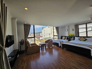 Hotelkamer met een groot bed, twee fauteuils, een tafeltje, een televisie en uitzicht over de stad.