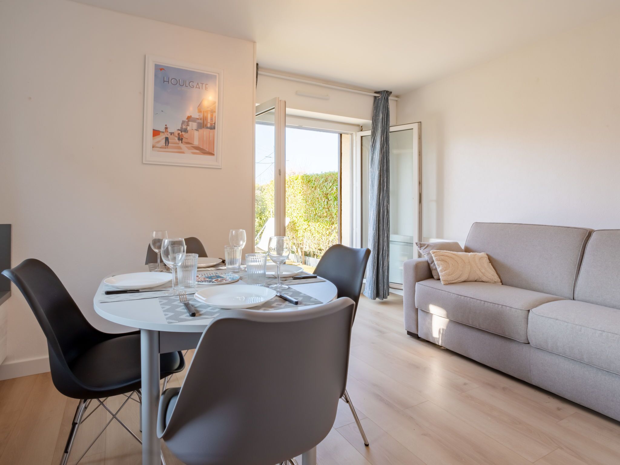 Una sala de estar moderna con comedor. Hay un sofá y una mesa preparada para cuatro personas.