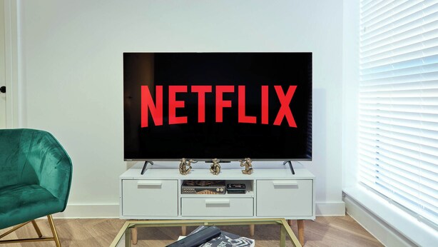 Una sala de estar moderna con un televisor de pantalla plana grande montado sobre un mueble blanco.
