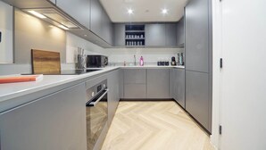 Una cocina moderna con armarios grises, encimera de madera y horno empotrado.