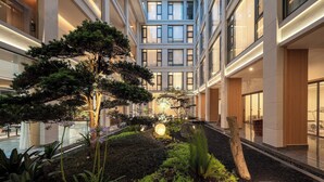 A modern building with a central courtyard featuring a large tree, various plants, and a well-lit walkway. - Z HOTEL - Qingchengshan (Chengdu)