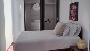 A bedroom with a bed, a wardrobe, and a painting on the wall.