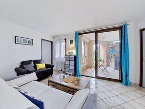 Una sala de estar con un sofá, una mesa de centro y un aparador. Hay una puerta corrediza de vidrio que da a un balcón.