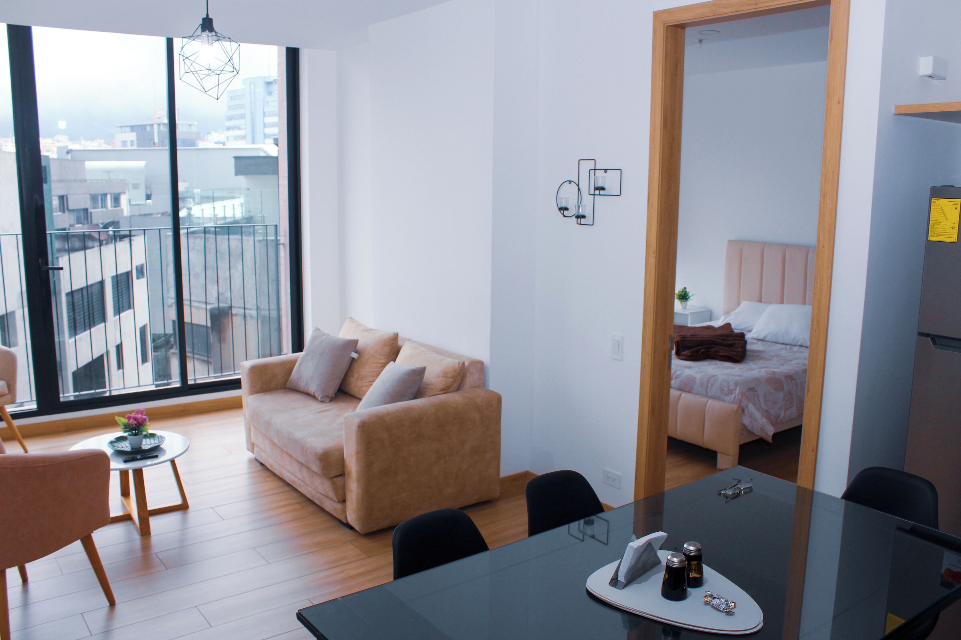 Un salon moderne avec un canapé, une table à manger et une vue sur la ville grâce à de grandes fenêtres.