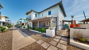 Calle residencial con casas con balcones, una acera pavimentada y zonas ajardinadas.