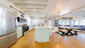 Una cocina amplia con una isla central, un comedor con una mesa larga y un espacio para sentarse.