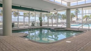 An indoor swimming pool with clear glass walls, a tiled floor, and a view of the outside. - Direct Gulf Front 1/1 Sleeps 6 (Orange Beach)