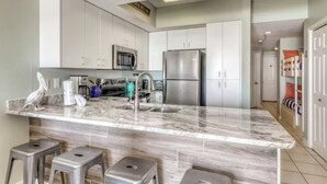 A modern kitchen with white cabinets, stainless steel appliances, and a marble countertop. - Direct Gulf Front 1/1 Sleeps 6 (Orange Beach)