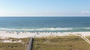 A beach with a wooden boardwalk leading to the shore, where people are sunbathing and walking. - Direct Gulf Front 1/1 Sleeps 6 (Orange Beach)