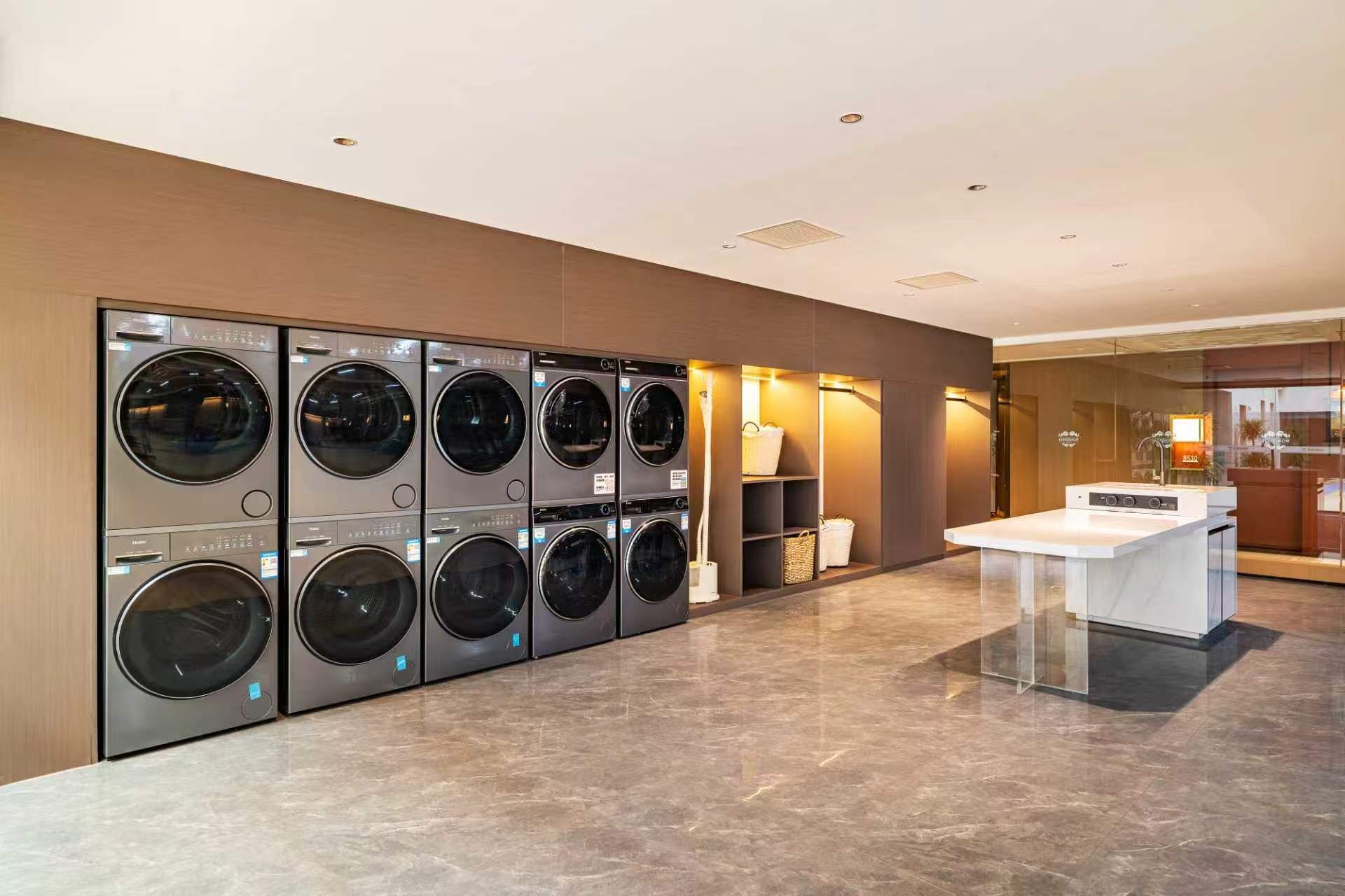 Un lavadero con varias lavadoras, un lavabo y un panel de vidrio.