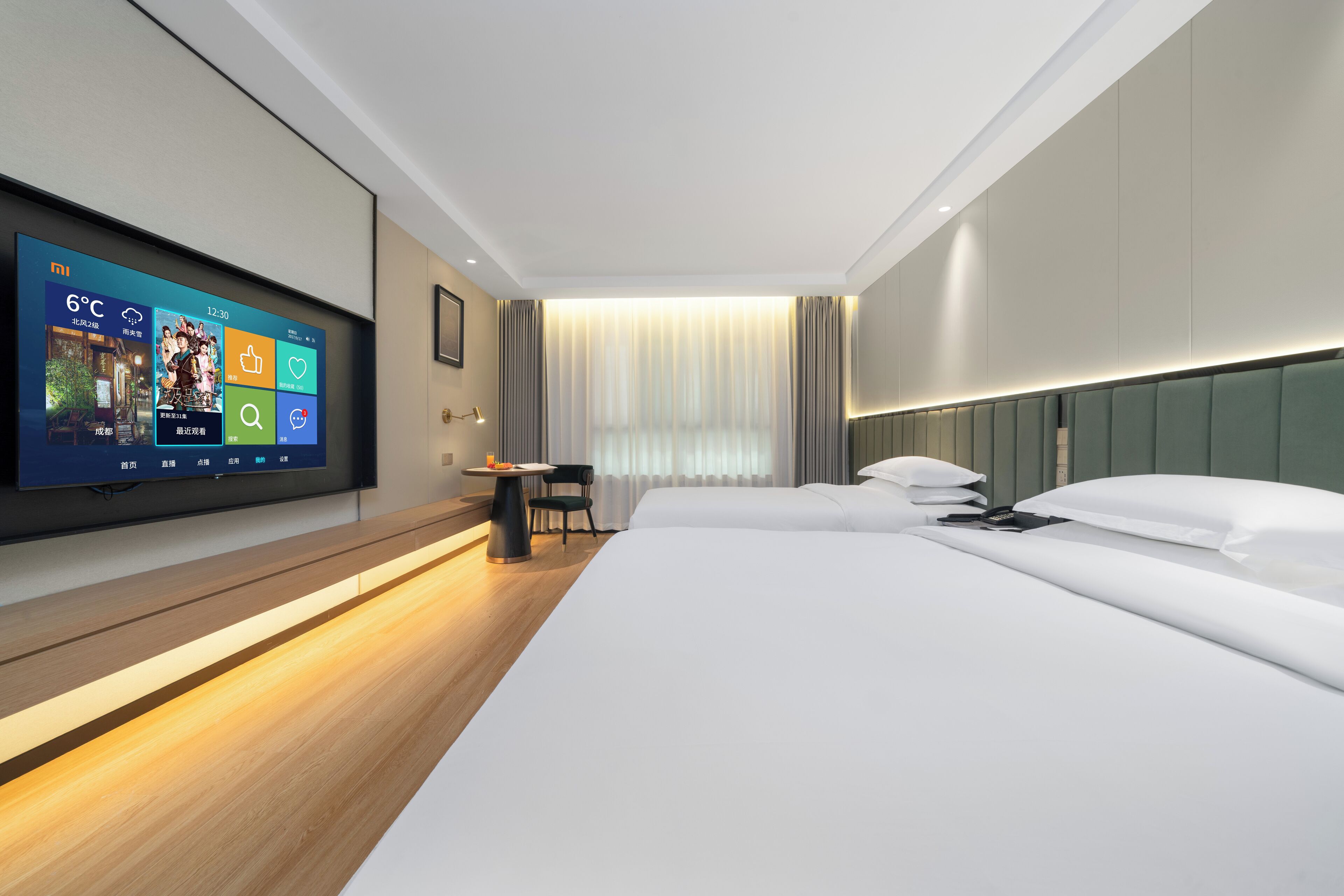 A modern hotel room with a large bed, a flat-screen TV mounted on the wall, a small table, and a chair.