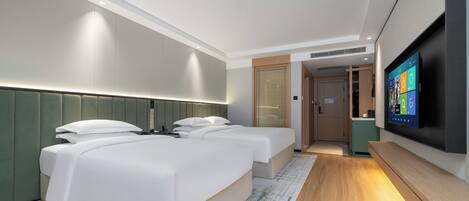 Ein modernes Hotelzimmer mit zwei Betten, einem Fernseher und einer kleinen Küchenzeile.