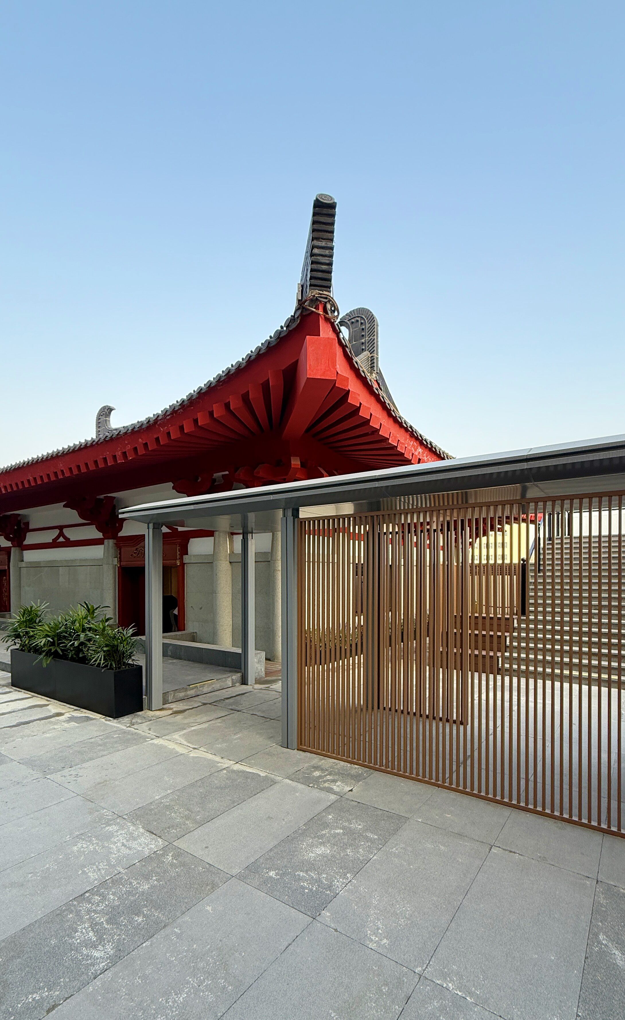 A traditional building with a red roof and a modern fence.