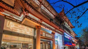 Un edificio tradicional con tejado de tejas, columnas grandes y escaparates de vidrio.