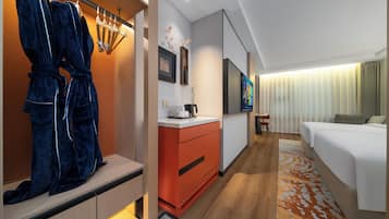 A modern hotel room with a wooden floor, a large bed, a desk with a chair, a wardrobe, and a TV.