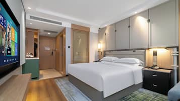 A hotel room with a bed, bedside table, and a TV mounted on the wall.