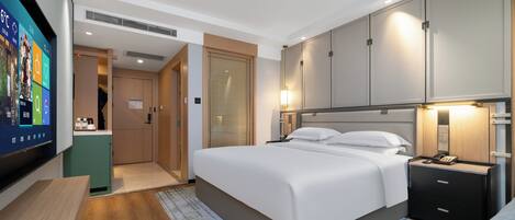 Een hotelkamer met een bed, nachtkastje en een aan de muur bevestigde televisie.