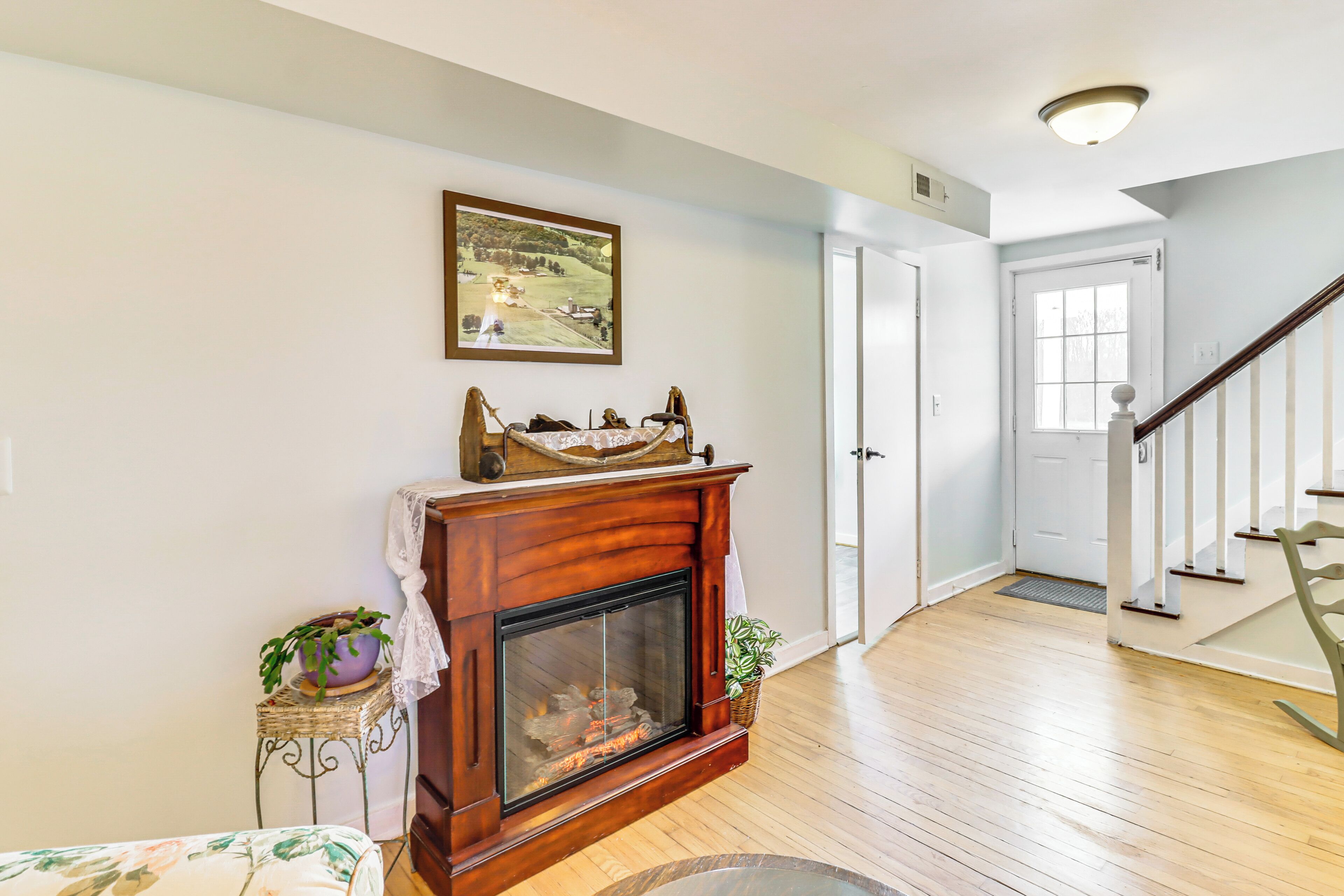 A living room with a fireplace, a staircase, and a door leading to another room.