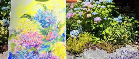 Una pintura de flores sobre un caballete, con un jardín al fondo.