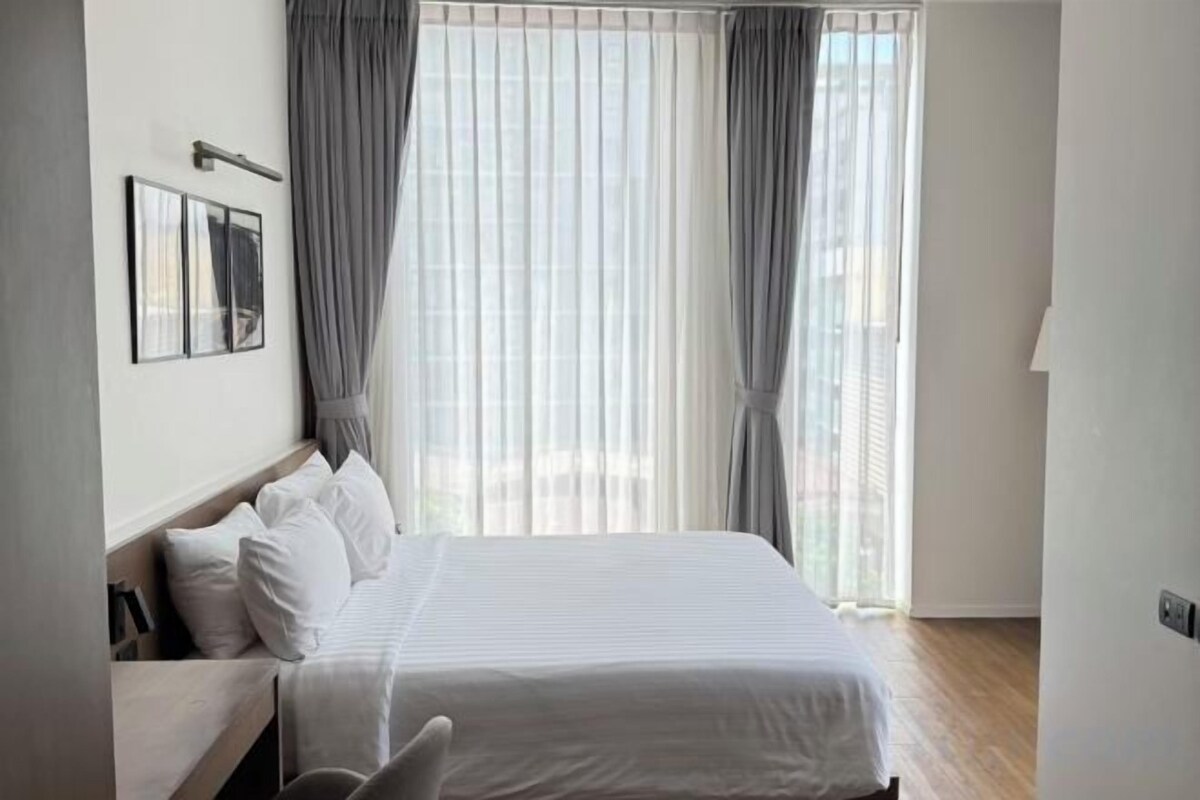 Une chambre d’hôtel avec un lit, une table de chevet et une fenêtre avec des rideaux.