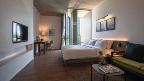Una habitación de hotel moderna con una cama grande, un sofá, un escritorio y un televisor.