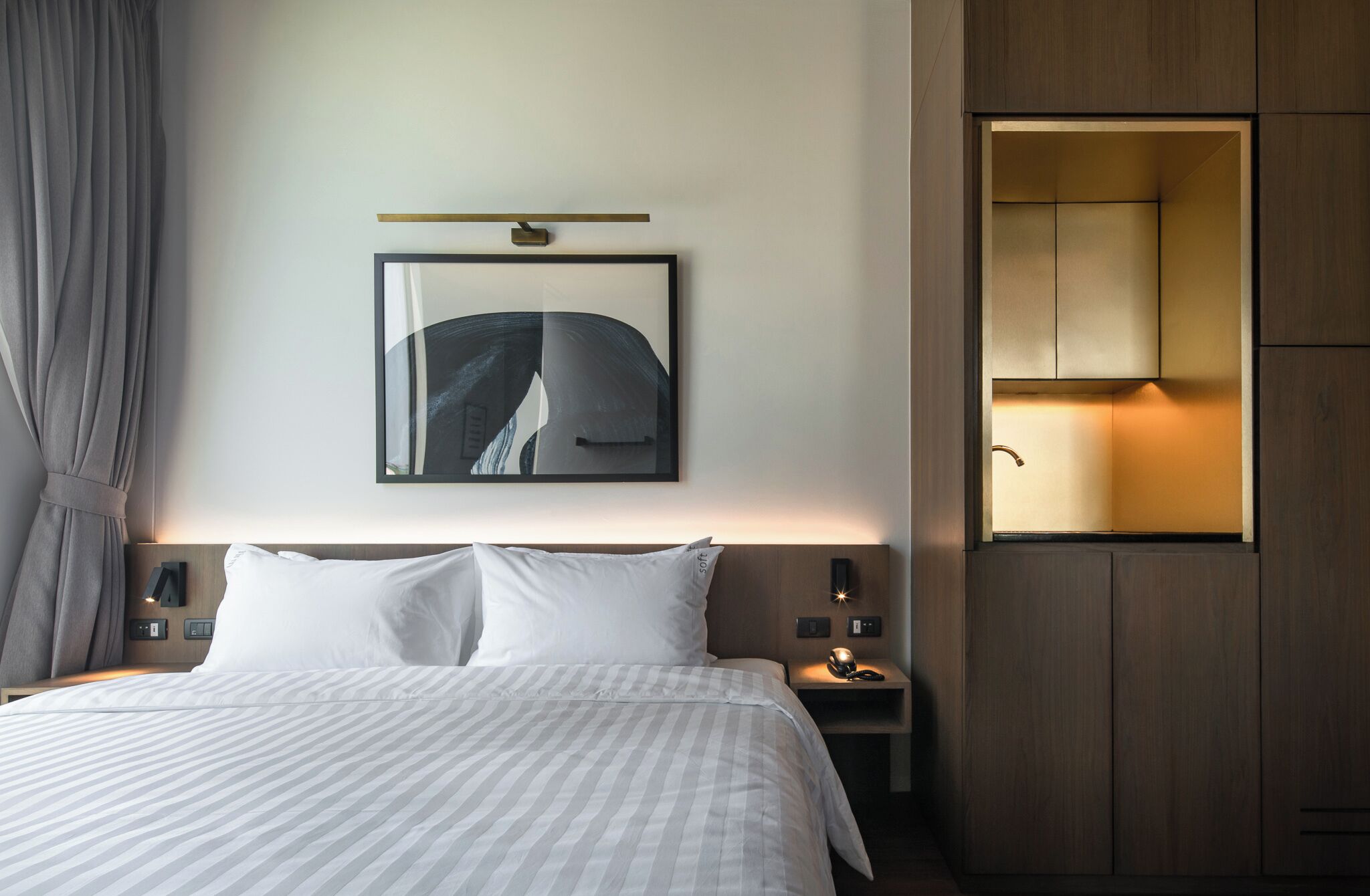 Una camera d'albergo con un letto, un comodino, un quadro appeso al muro e un armadio a muro.