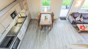 Een moderne keuken met een eethoek, een bank en een raam met uitzicht op groen.