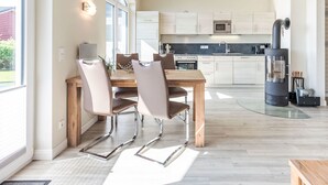 A modern kitchen with a dining area, featuring a wooden table, chairs, and a built-in stove. - Luv & Lee by Interhome (Dagebüll)