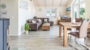 A spacious living area with a wooden ceiling, a sofa, a coffee table, and a dining table with chairs. - Luv & Lee by Interhome (Dagebüll)
