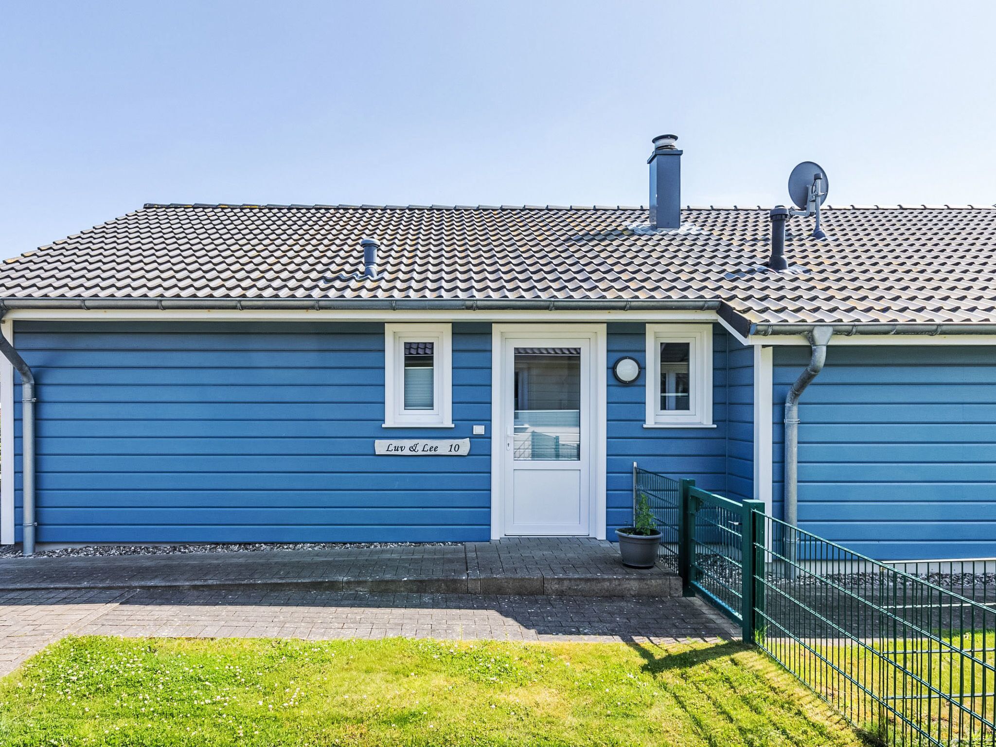 A blue house with a tiled roof, a white door, and a small window.