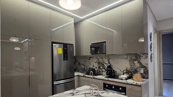 Una cocina moderna con encimera de mármol, electrodomésticos de acero inoxidable e iluminación integrada.