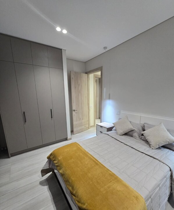 A bedroom with a bed, bedside table, and wardrobe. - Departamento de lujo Quito Le Parc -1002 (Quito)