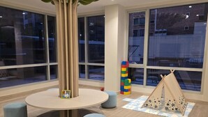 A children's play area with a large tree-shaped light fixture, round table, and ottomans. - Departamento de lujo Quito Le Parc -1002 (Quito)