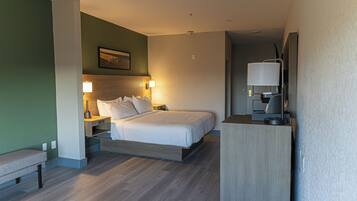 A modern hotel room with a bed, bedside tables, a bench, and a TV.