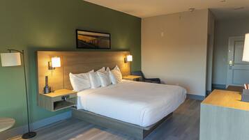 Une chambre d’hôtel moderne avec un grand lit, des tables de chevet, une petite table, un bureau et une chaise.
