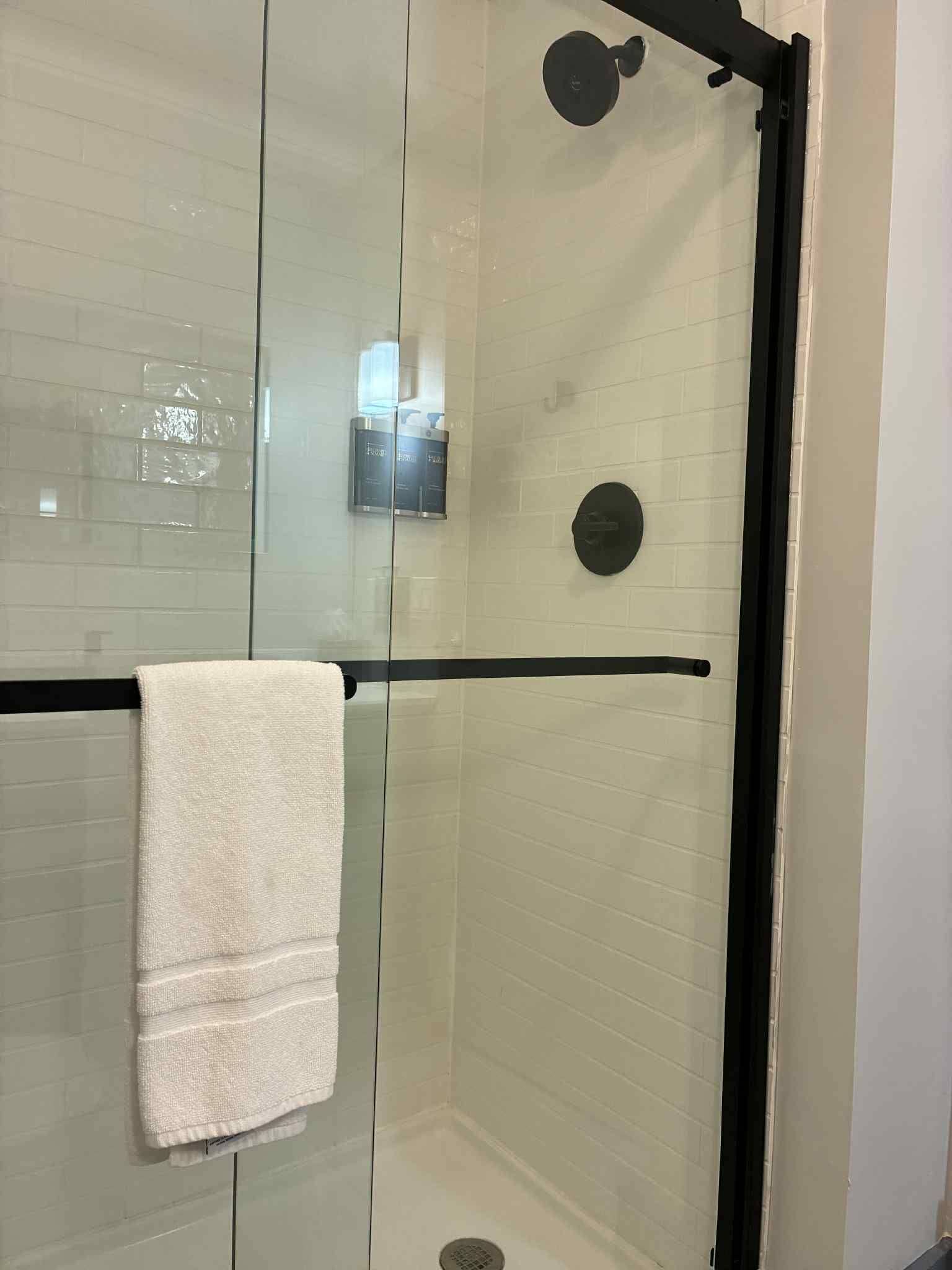 Una ducha con cerramiento de vidrio y una toalla colgada en el pomo de la puerta.