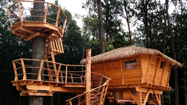 Una casa en árbol de madera con techo de paja y escalera en espiral.