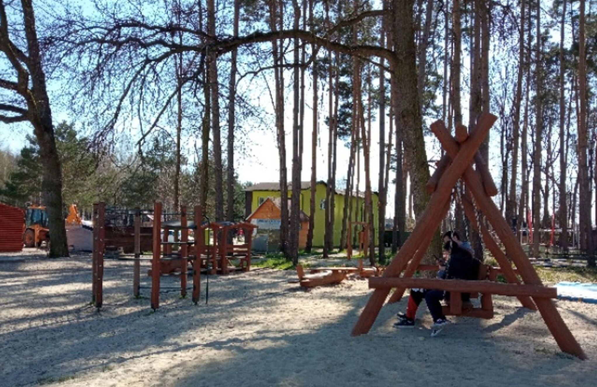 Ein Spielplatz mit Schaukeln und Klettergerüsten inmitten eines bewaldeten Geländes.