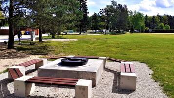 Un parco con un'area salotto circolare, con panche e un braciere al centro.