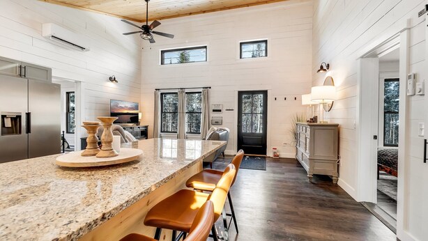 A spacious kitchen with a granite countertop, wooden bar stools, and a ceiling fan.