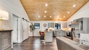 A modern kitchen with a central island, grey cabinets, stainless steel appliances, and a wooden ceiling. - Charming 2-bedroom chalet with jacuzzi WiFi and AC in Glenburn (Glenburn)