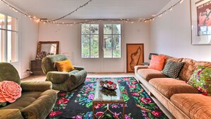 A cozy living room with a green armchair, a brown sofa, and a floral rug. There is a window with a view of greenery outside. - Sauzelle by Interhome (Ile d'Oléron)