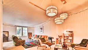 A spacious living room with a large window, a fireplace, and a cozy seating area with a coffee table and bookshelves. - Sauzelle by Interhome (Ile d'Oléron)