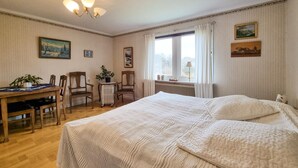A bedroom with a large bed, a wooden desk, two chairs, a radiator, and a window with curtains. - 3 bedroom amazing home in Dyrön (Dyrön)