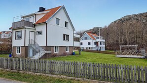 A modern two-story house with a sloped roof, a wooden deck, and a fenced yard. - 3 bedroom amazing home in Dyrön (Dyrön)