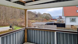A balcony with a view of a residential area, including a house with a red roof and a wooden deck. - 3 bedroom amazing home in Dyrön (Dyrön)