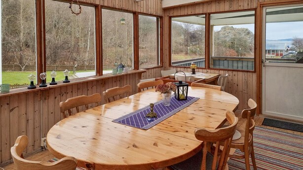 A wooden dining table with chairs, a vase with flowers, and a lantern. - 3 bedroom amazing home in Dyrön (Dyrön)